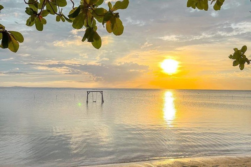 A calm sea at sunset with a swing set in the distance. 5