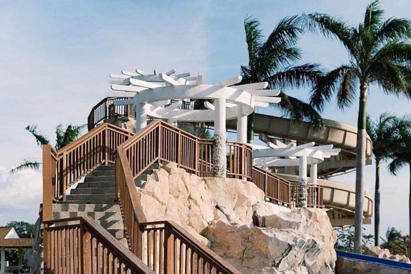 A staircase with wooden railings, a rock formation, and a white structure with a curved roof. 4