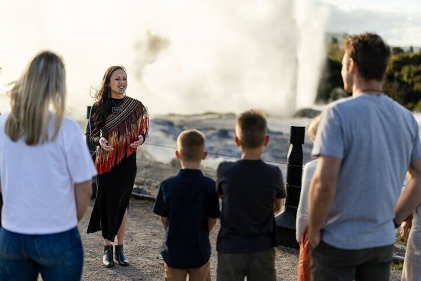 A group of people observing a geyser eruption. 1