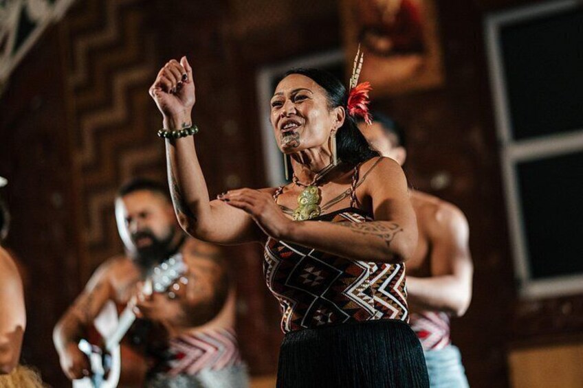 A person in traditional attire with a patterned garment and feather headdress, performing a dance. 4
