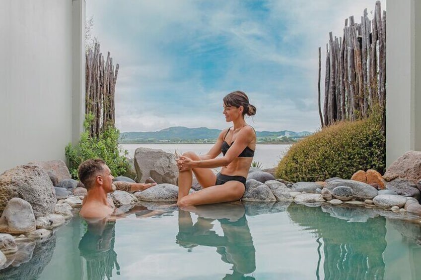 A couple in a hot spring with a scenic view of mountains and a wooden fence. 2