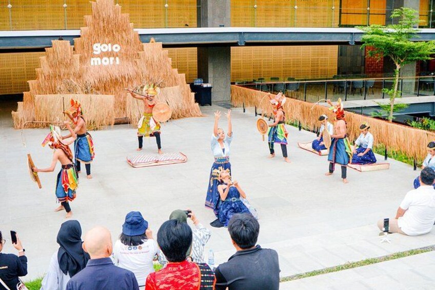 A traditional dance performance outdoors with a modern building in the background. 1