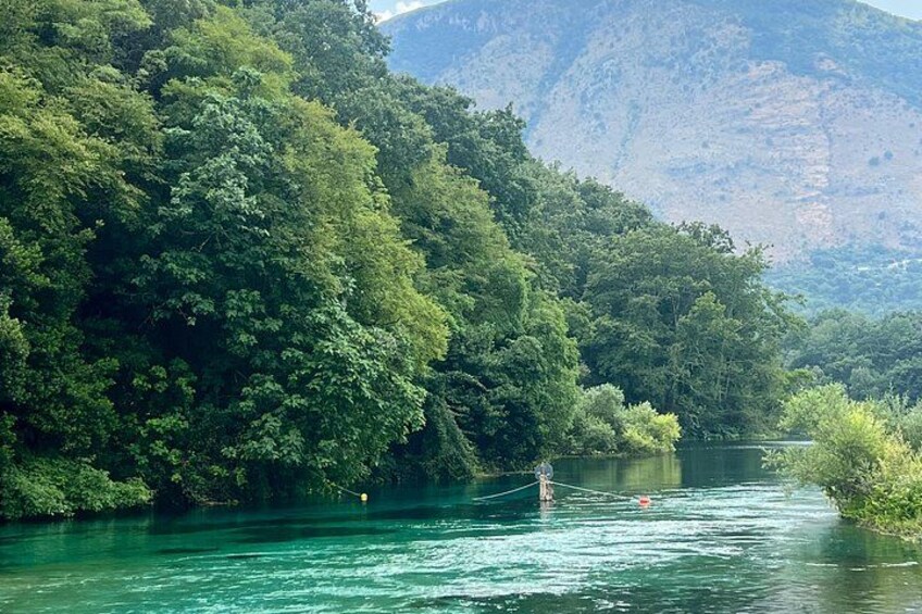 Een rivier omgeven door dicht groen bos en bergen op de achtergrond. 1