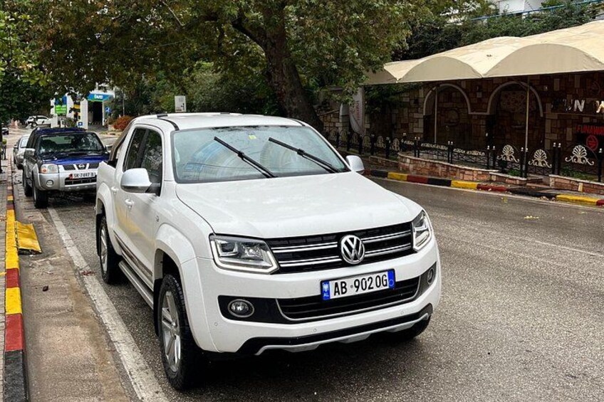 Een witte Volkswagen SUV op een stadsstraat met bomen en een gebouw op de achtergrond. 2
