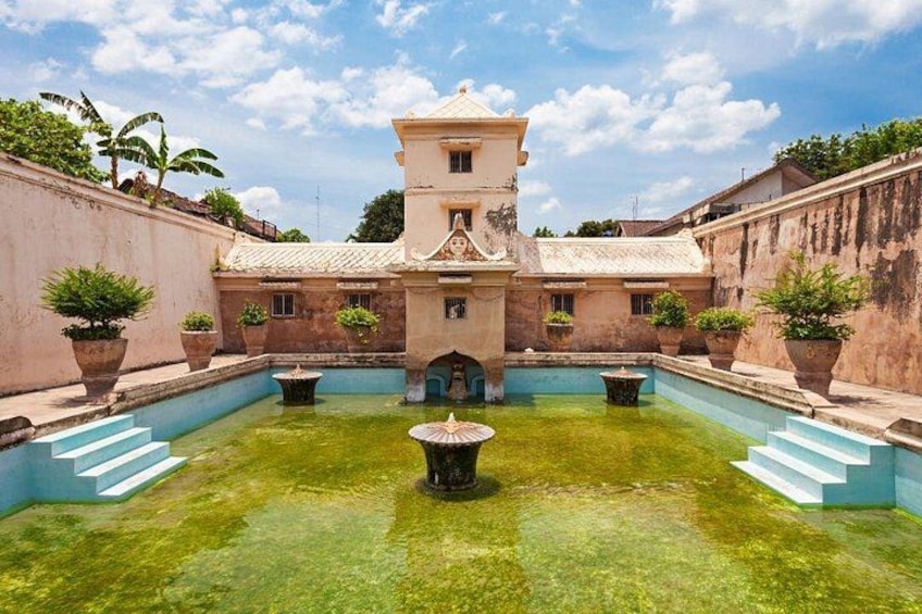 Ein Innenhof mit einem zentralen Brunnen, umgeben von Gebäuden mit Terrakotta-Dächern und -Mauern. 2