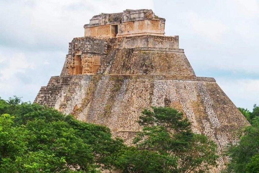 Una gran estructura parecida a una pirámide con una parte superior plana, rodeada de densa vegetación verde. 2