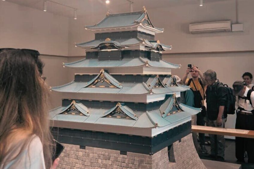 A multi-tiered structure resembling a pagoda with a tiled roof, surrounded by people. 4
