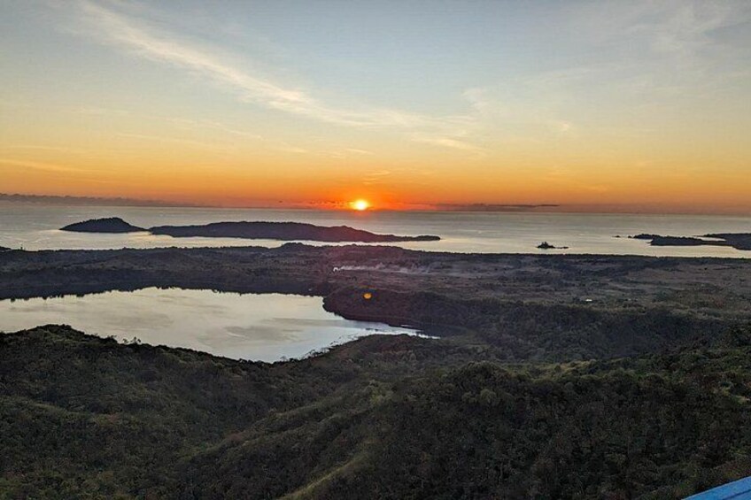 A sunset over a coastal landscape with water bodies and hills. 1