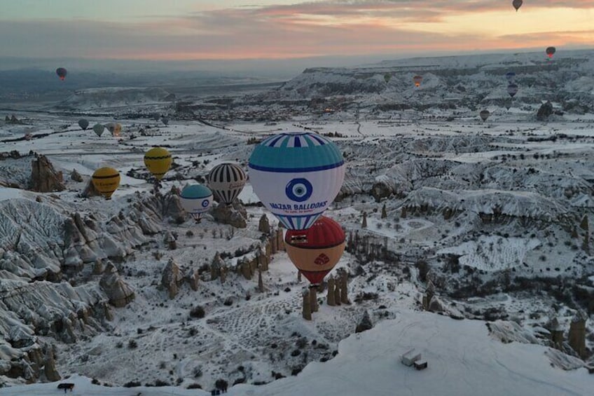 A snowy landscape with multiple hot air balloons. 5