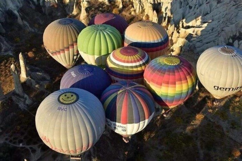 A group of colorful hot air balloons parked on rocky terrain. 1