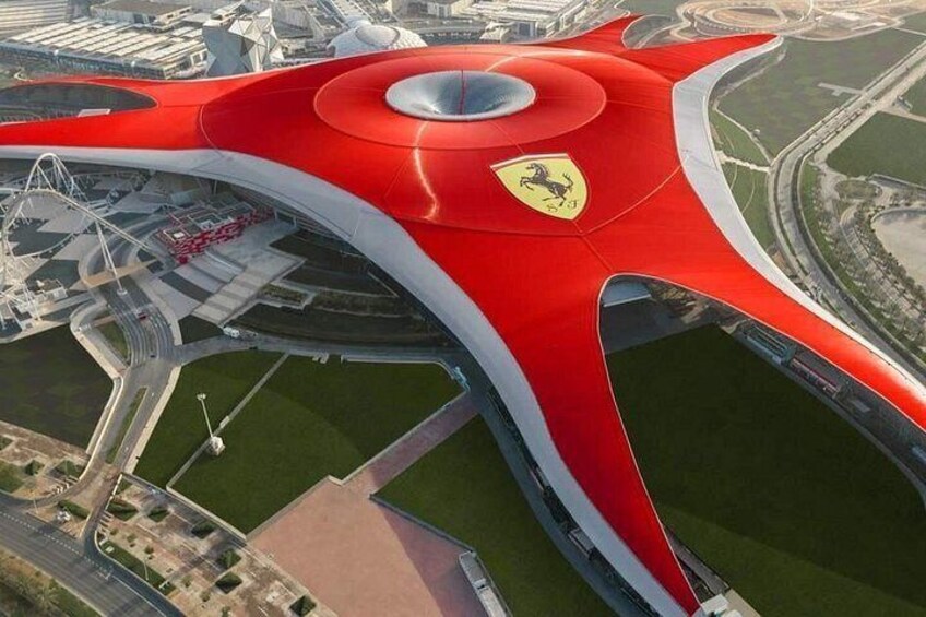 Een rood Ferrari-logo op een modern gebouw met een golvend dak. 5