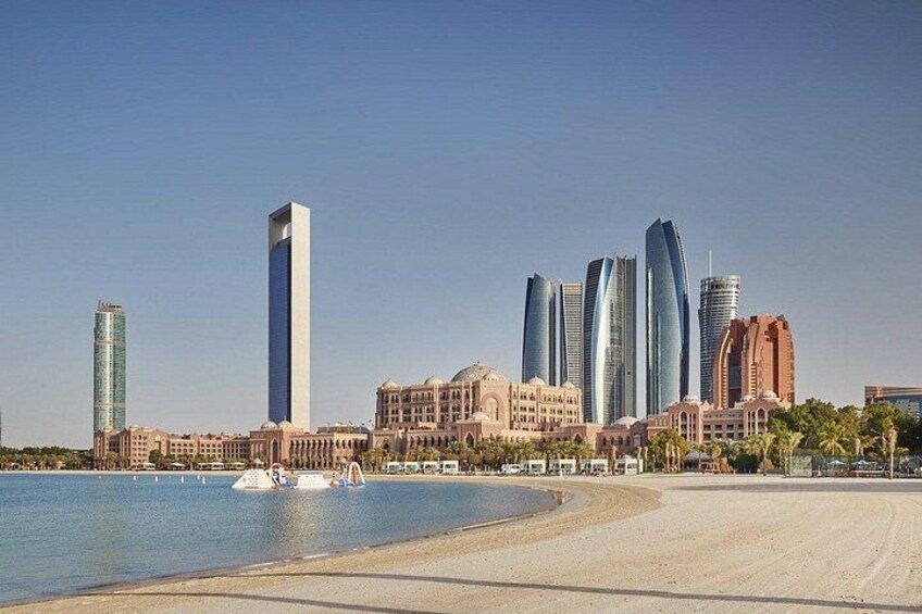 A coastal cityscape with modern skyscrapers, a sandy beach, and a calm sea. 2