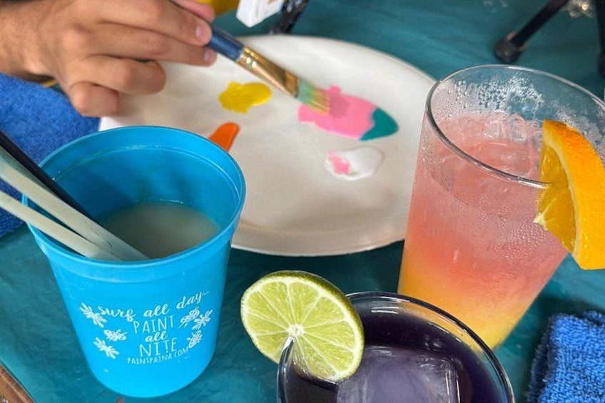 A blue cup with a spoon, a glass with a lime wedge and an orange slice, and a plate with colorful designs. 2