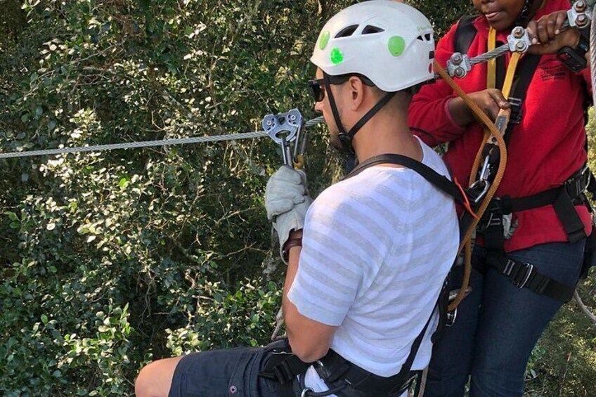 Una persona con casco y arnés preparándose para una tirolesa. 3