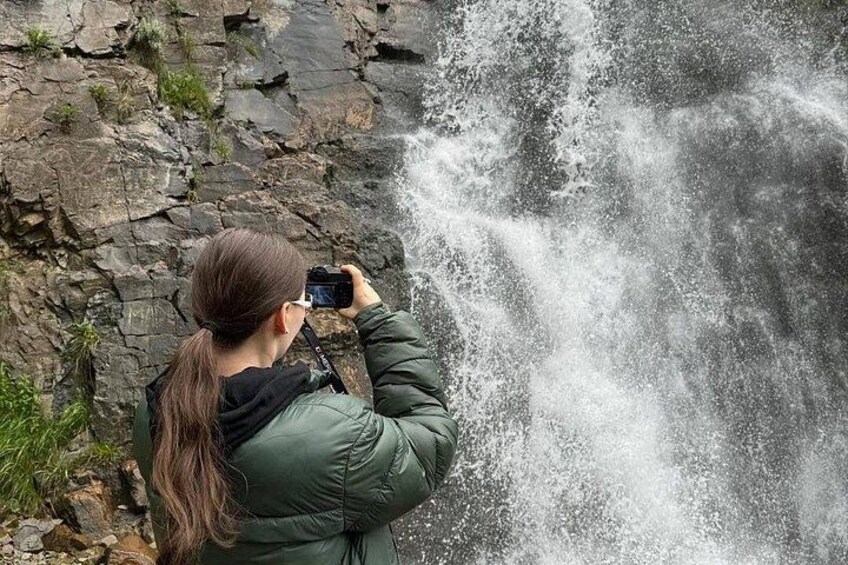 A person taking a photograph of a waterfall. 4