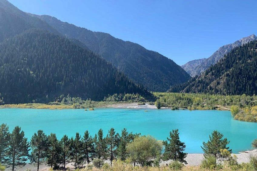 A turquoise lake surrounded by dense forests and mountains. 1