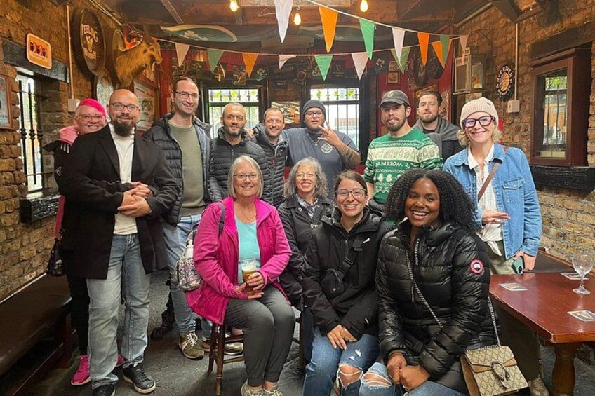 En gruppe mennesker i en hyggelig pub med trævægge og en murstensgulv. 3