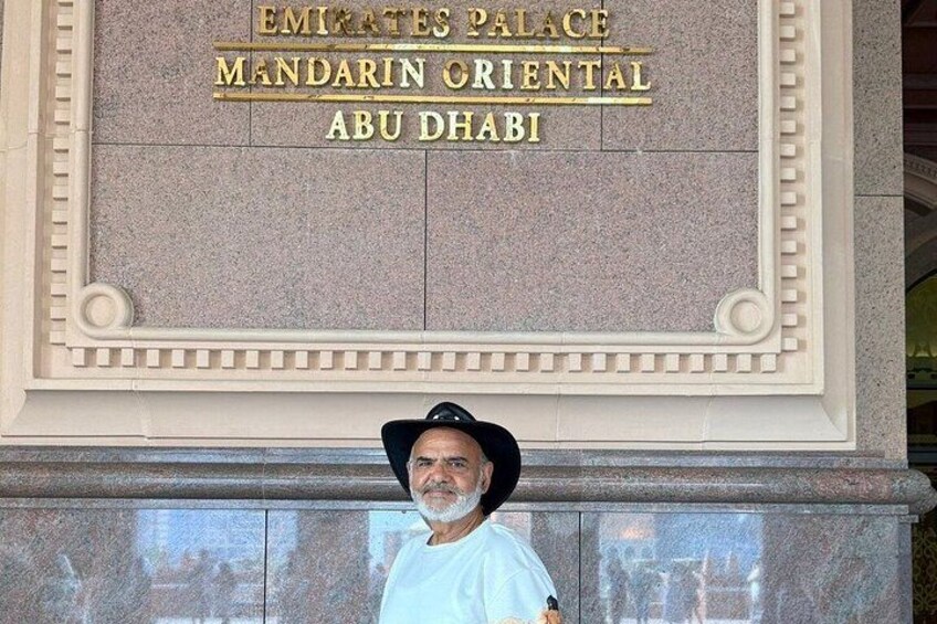 Ein Mann steht vor dem Schild des Emirates Palace, auf dem 'MANDARIN ORIENTAL ABU DHABI' steht. 3