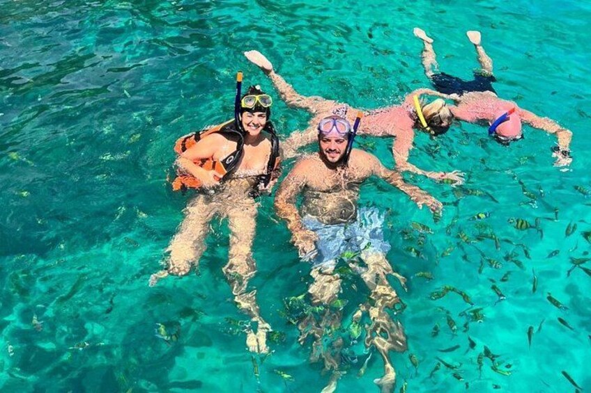 Tre persone che fanno snorkeling in acqua cristallina. 3