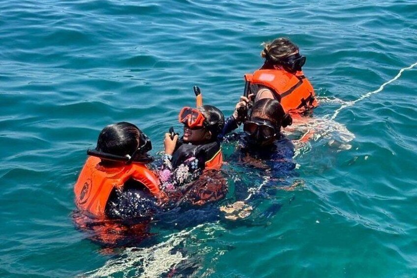 Un gruppo di persone in acqua, indossa giubbotti di salvataggio arancioni e attrezzatura subacquea. 4