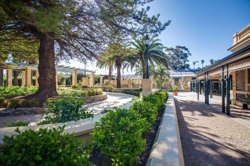 A landscaped garden with pathways, trees, and a building with columns. 5