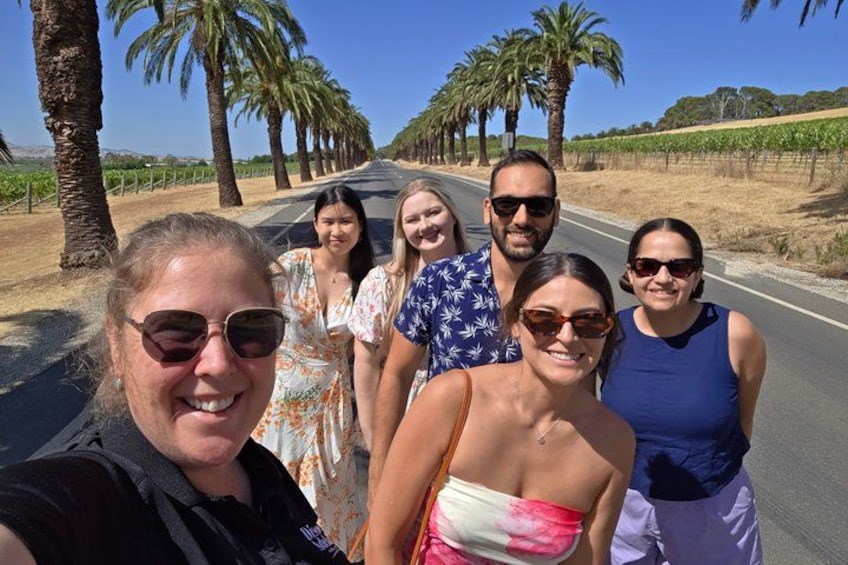 A group of people on a road lined with palm trees. 1