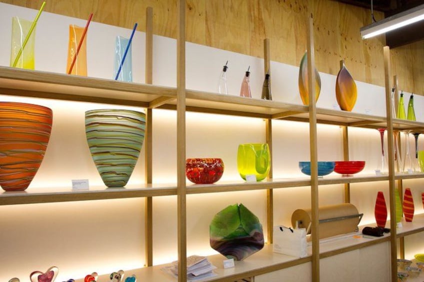 A display of colorful glass bowls and vases on shelves. 2