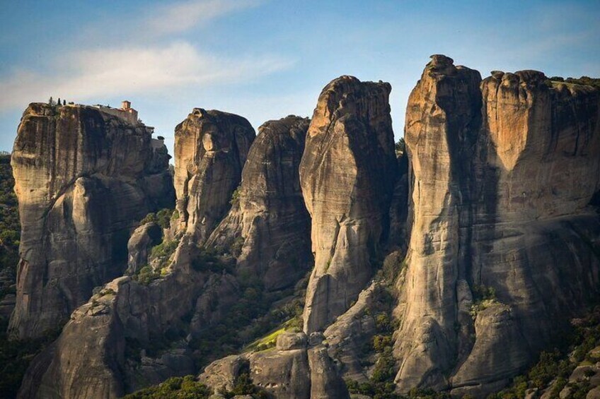 A series of tall, rugged rock formations with a small building on the left. 2
