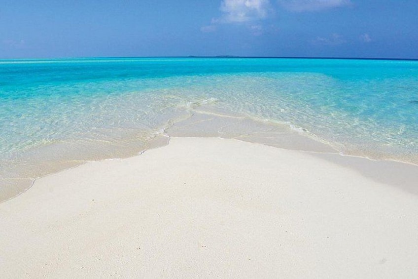 A beach with clear turquoise water and white sand. 1