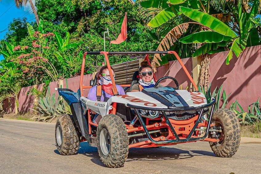 A person in a red and white ATV with large tires, parked on a paved road. 2