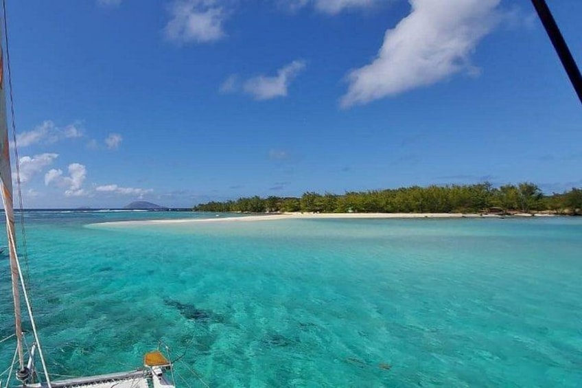 A turquoise sea, a sandy beach, and a forested island in the distance. 1
