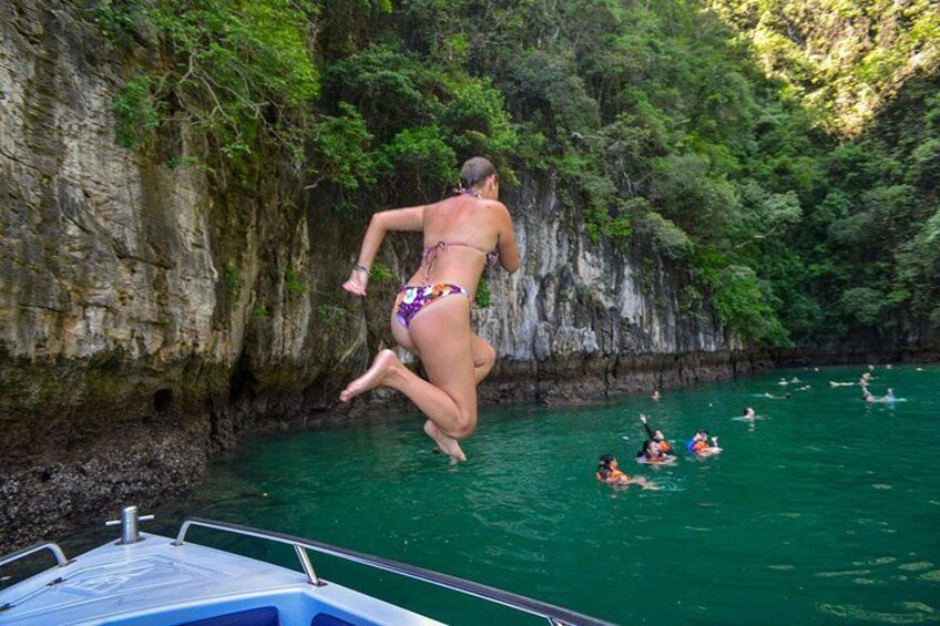 Una persona saltando desde un bote hacia el agua, rodeada de acantilados. 2