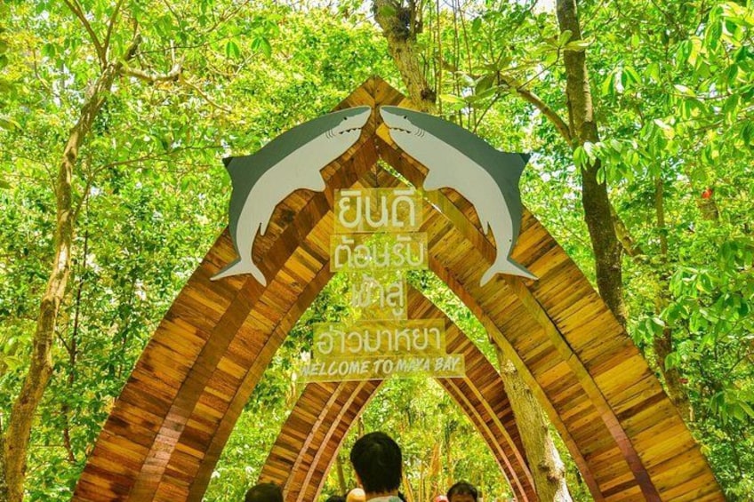 Un arco de madera con la silueta de un tiburón y texto tailandés dando la bienvenida a los visitantes a la Bahía Tom Yum. 5