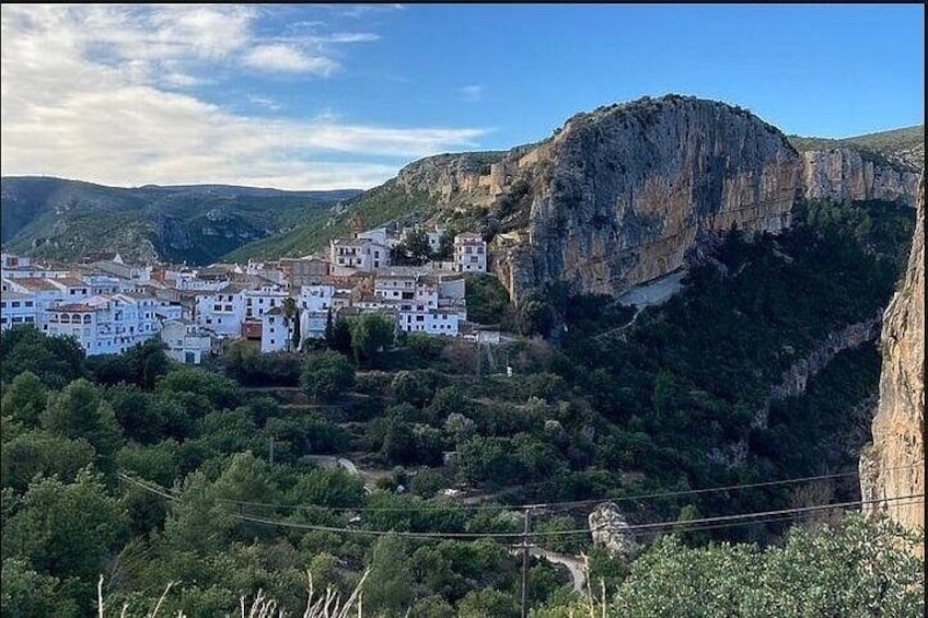 A town nestled in a valley with a prominent cliff in the background. 3