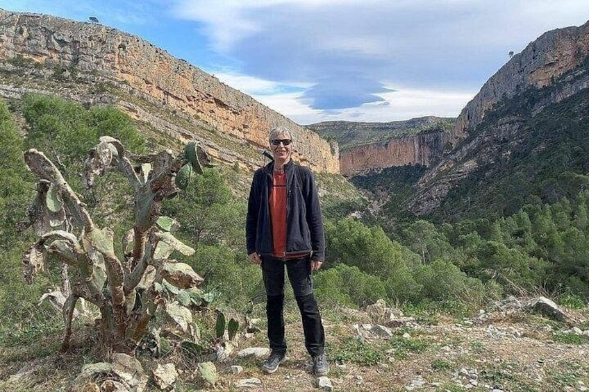 A person standing in a desert landscape with cacti and rocky terrain. 1