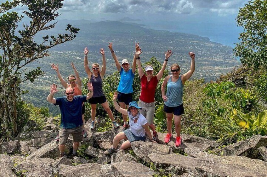 A group of people standing on rocky terrain with a scenic view of a valley and mountains in the background. 1