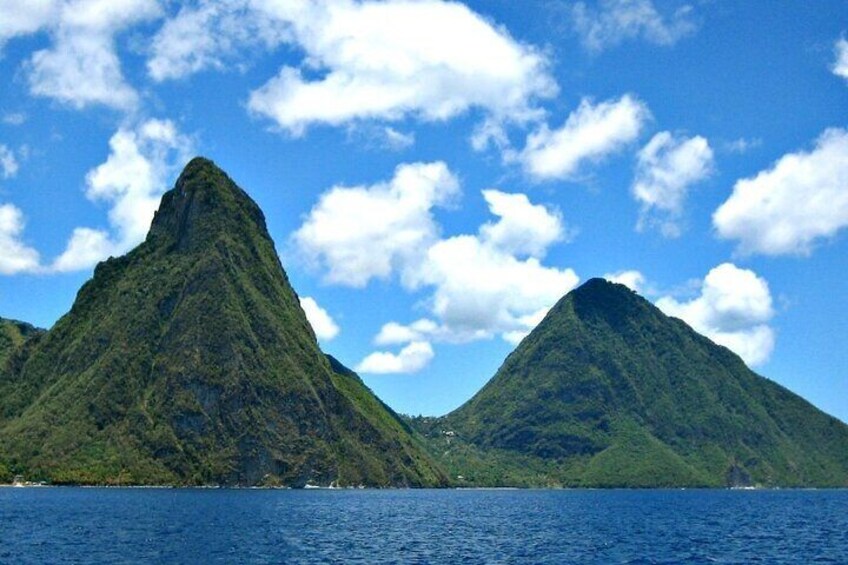 Two green mountains with a clear blue sky and calm water. 2