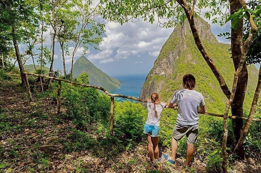 Two people standing on a forested path with a mountain in the background. 5