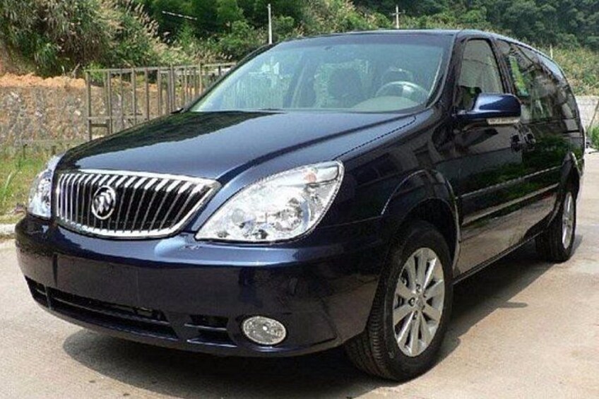 Un SUV nero parcheggiato su una superficie asfaltata, con una recinzione e vegetazione sullo sfondo. 2