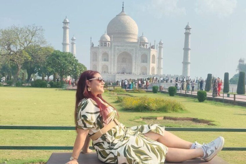 En person sidder på en bænk med Taj Mahal i baggrunden. 4