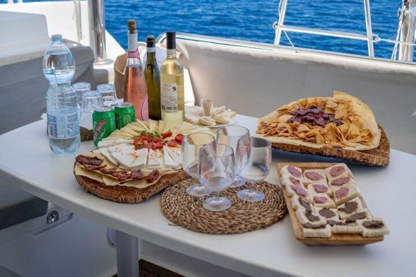 A table with various cheeses, cured meats, and bread on a boat. 2