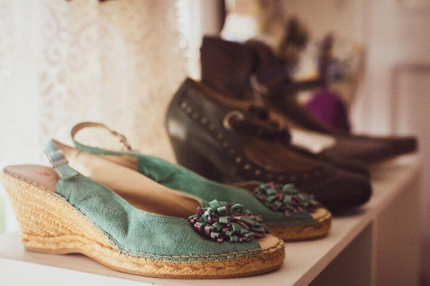 A pair of green wedge sandals with decorative bows on a shelf. 3