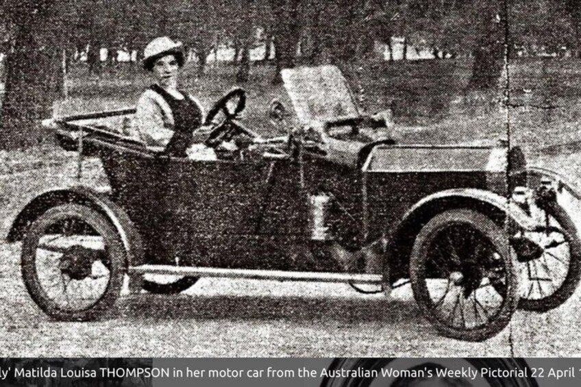 A vintage car with a woman driving. 4