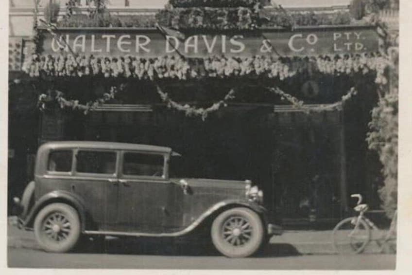 A vintage car parked in front of a building with a sign reading 'Walter Davis & Co. Ltd.' 2