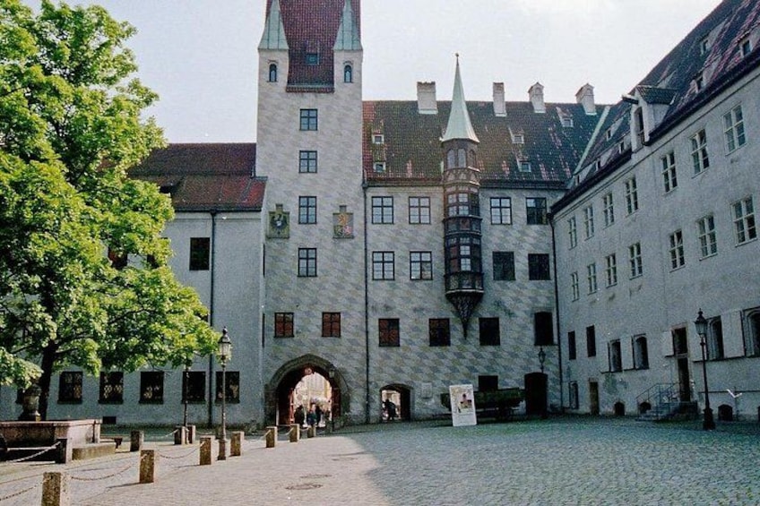 A historic building with a tower, a cobblestone courtyard, and a tree. 3