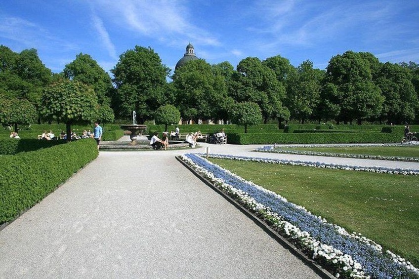 A park with a central pathway, manicured lawns, and a dome-shaped structure in the background. 5