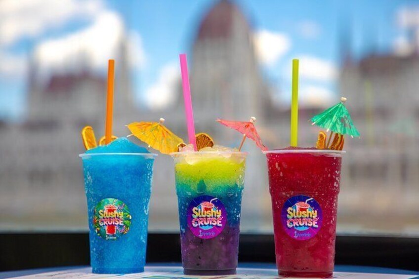 Three colorful Slushy Cruise drinks with straws and umbrellas on a table. 1