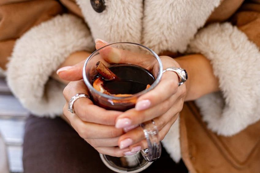 A person holding a glass mug with a cinnamon stick. 2