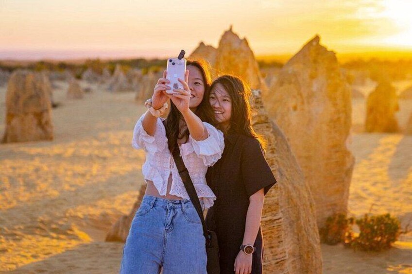 Dos personas tomándose un selfie con un teléfono inteligente en un paisaje desértico con grandes formaciones rocosas. 4