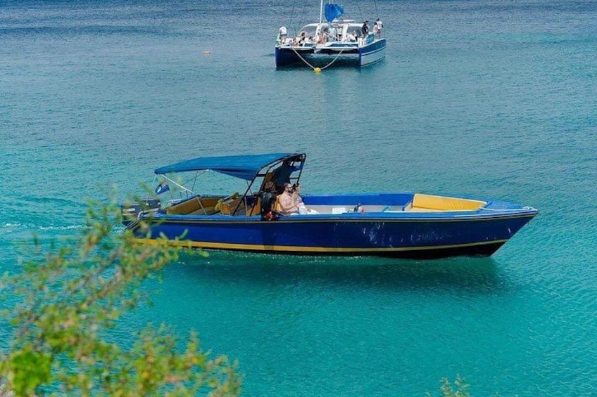 Un velero azul con toldo amarillo sobre aguas turquesas, con otro barco al fondo. 2